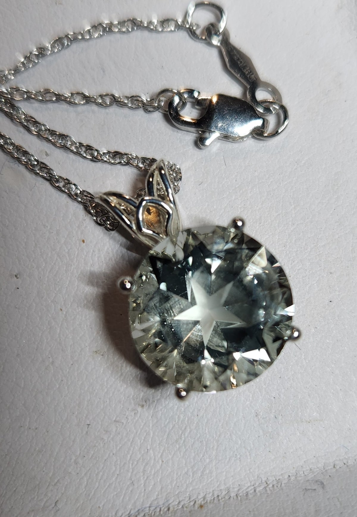 7.67ct clear star brilliant cut Texas topaz is set in a sterling silver scroll pendant and chain.