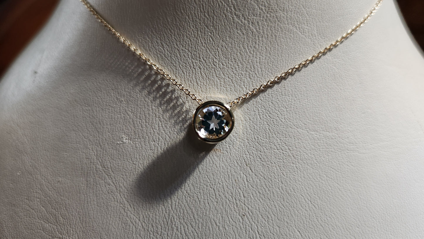 0.95 ct clear star brilliant cut Texas topaz is set in a 14kt gold bezel slide pendent on a gold chain.