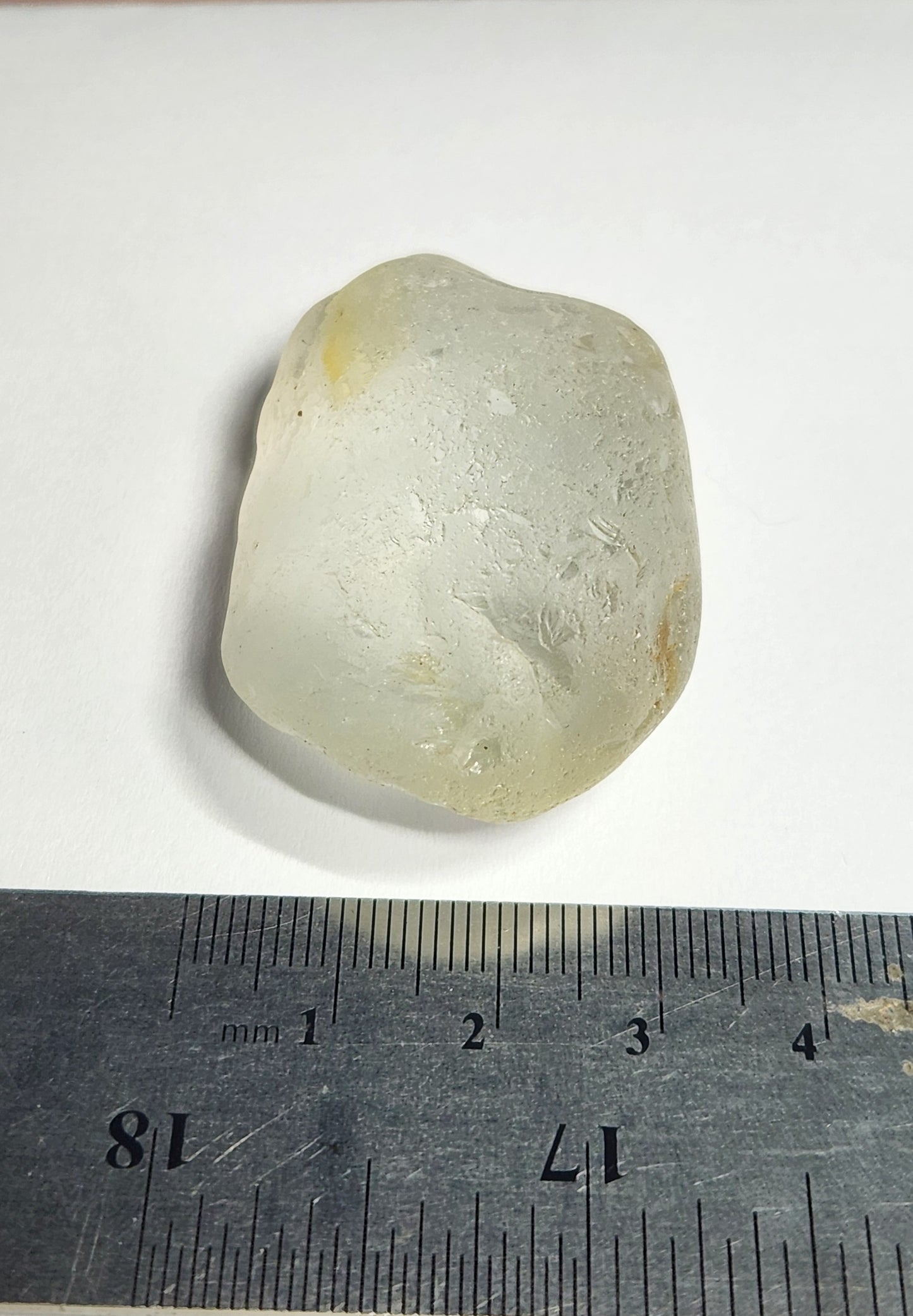 Translucent stone with visible texture on a white background, measured against a ruler.