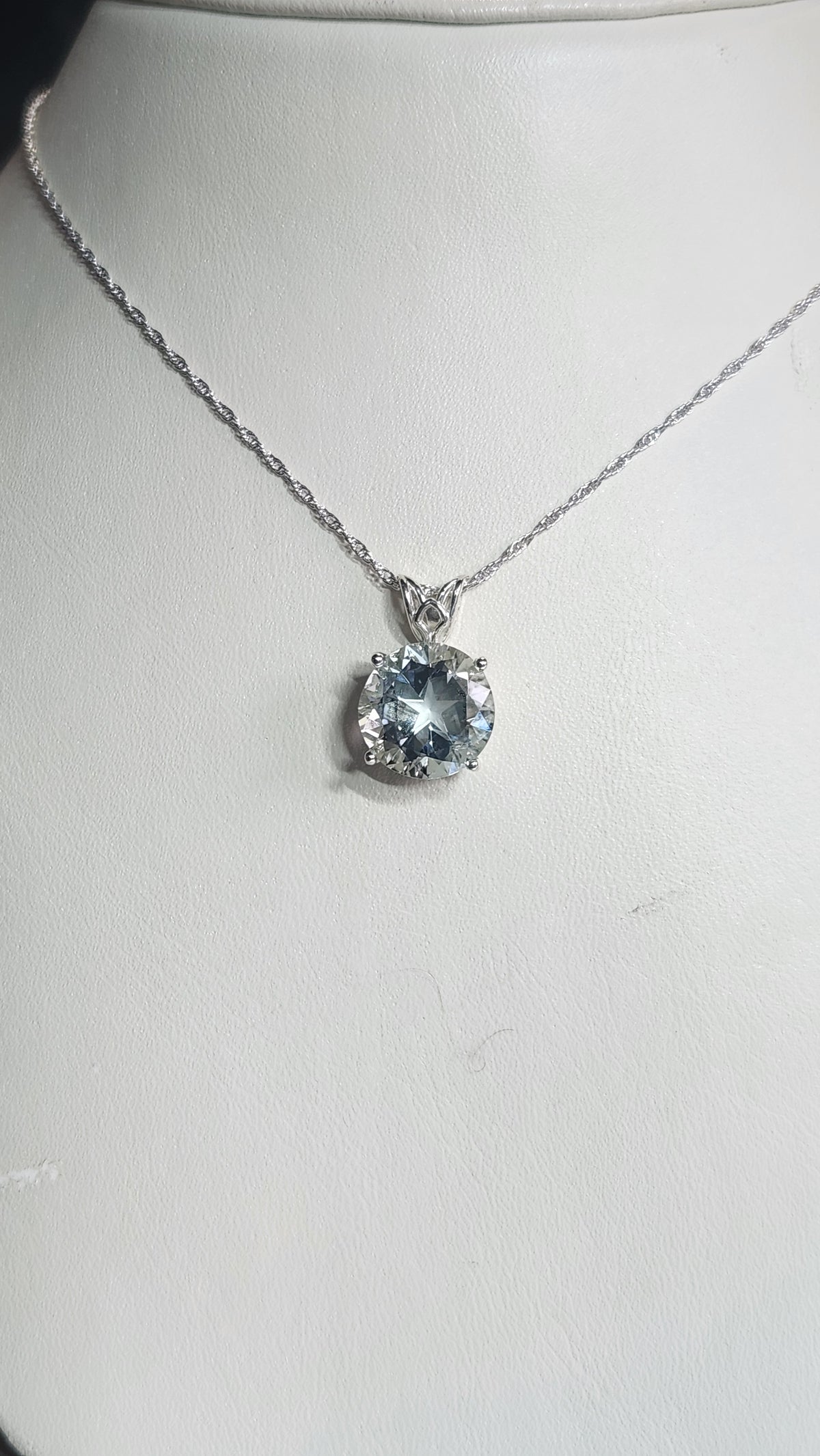 7.67ct clear star brilliant cut Texas topaz is set in a sterling silver scroll pendant and chain.