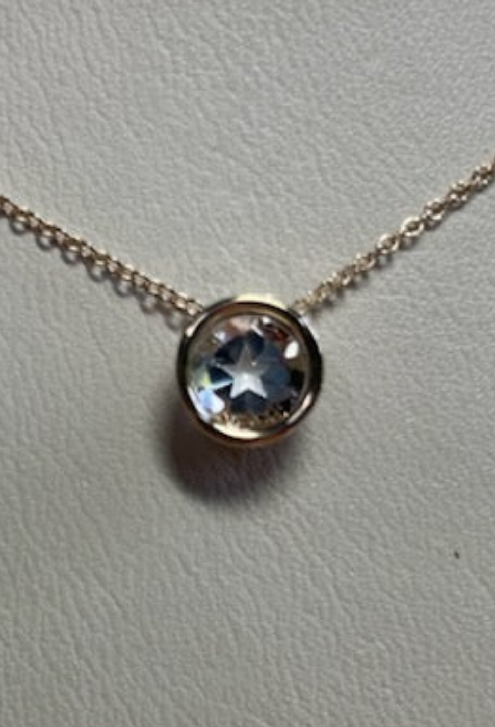 0.95 ct clear star brilliant cut Texas topaz is set in a 14kt gold bezel slide pendent on a gold chain.